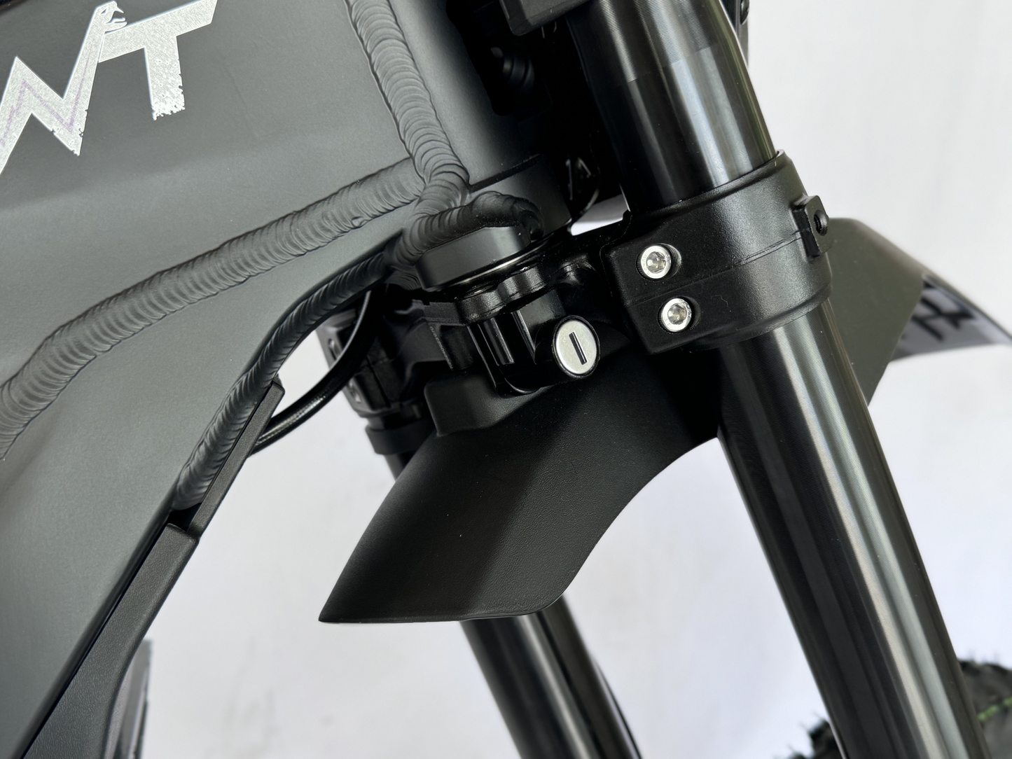 Close-up of a motorcycle's headlight assembly with 'NT' branding on a blurred background.