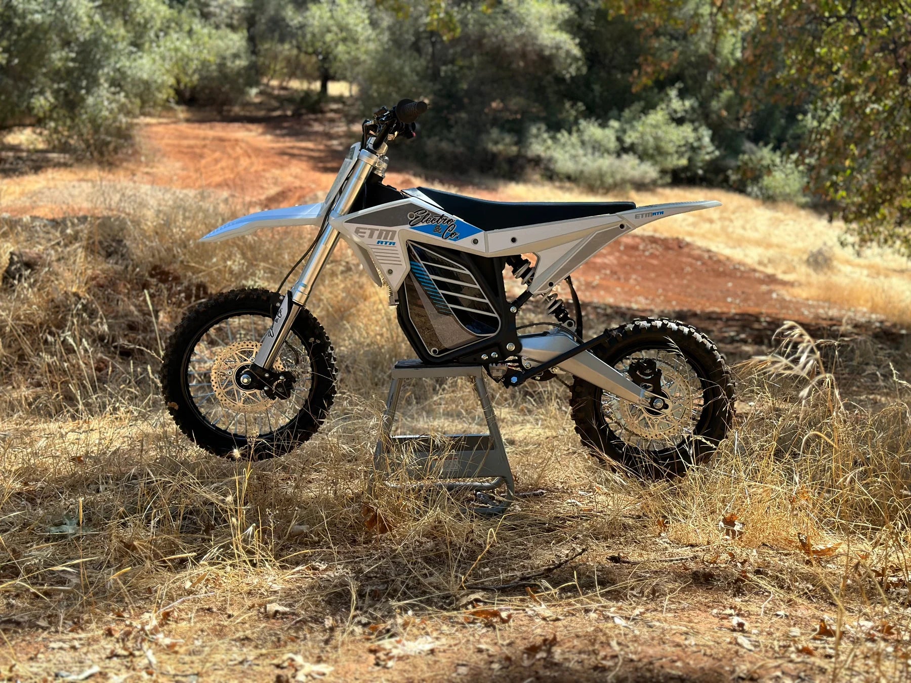 Electric dirt bike on a dirt path with trees in the background