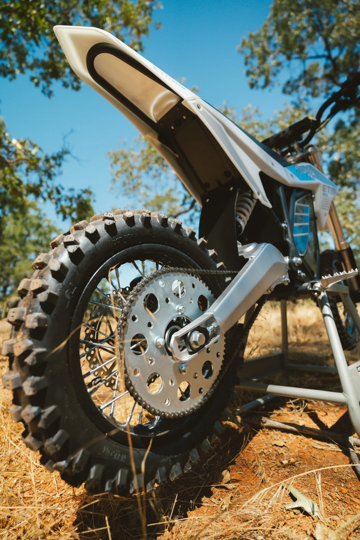 Close-up of a dirt bike's rear wheel and chain on a natural background